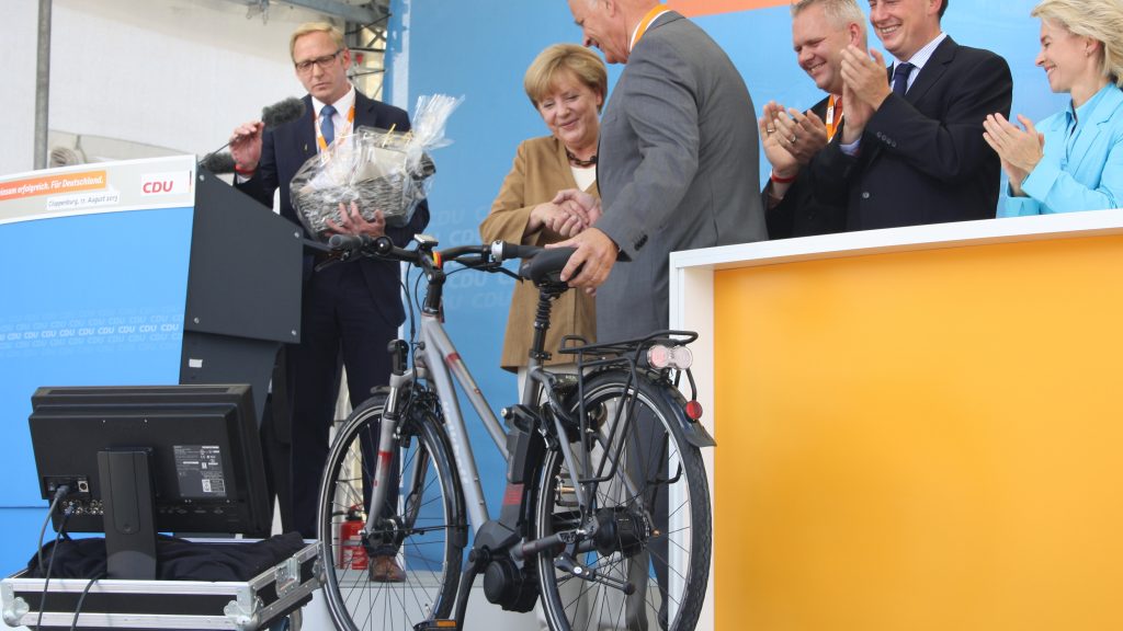 Der Cloppenburger Landrat Hans Eveslage übergibt Bundeskanzlerin Angela Merkel das neue Kanzleramt-E-Bike Kalkhoff Agattu Impulse 8 HS.